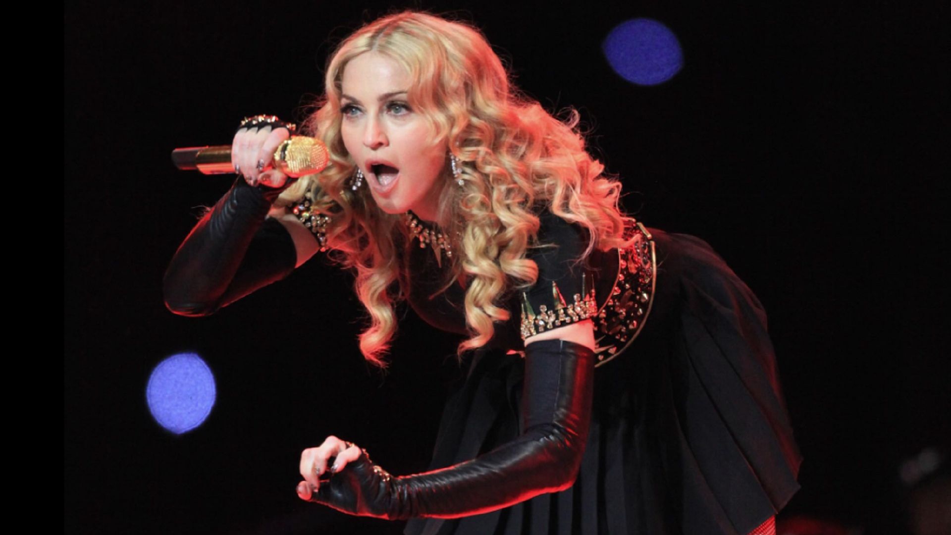 Madonna sings into the microphone, leaning forward