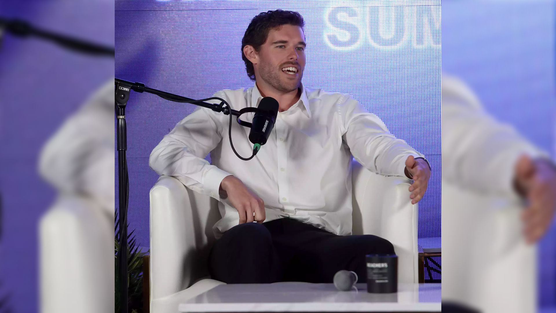 The son of actor Arnold Schwarzenegger sits in a white shirt across from the microphone and looks to the side