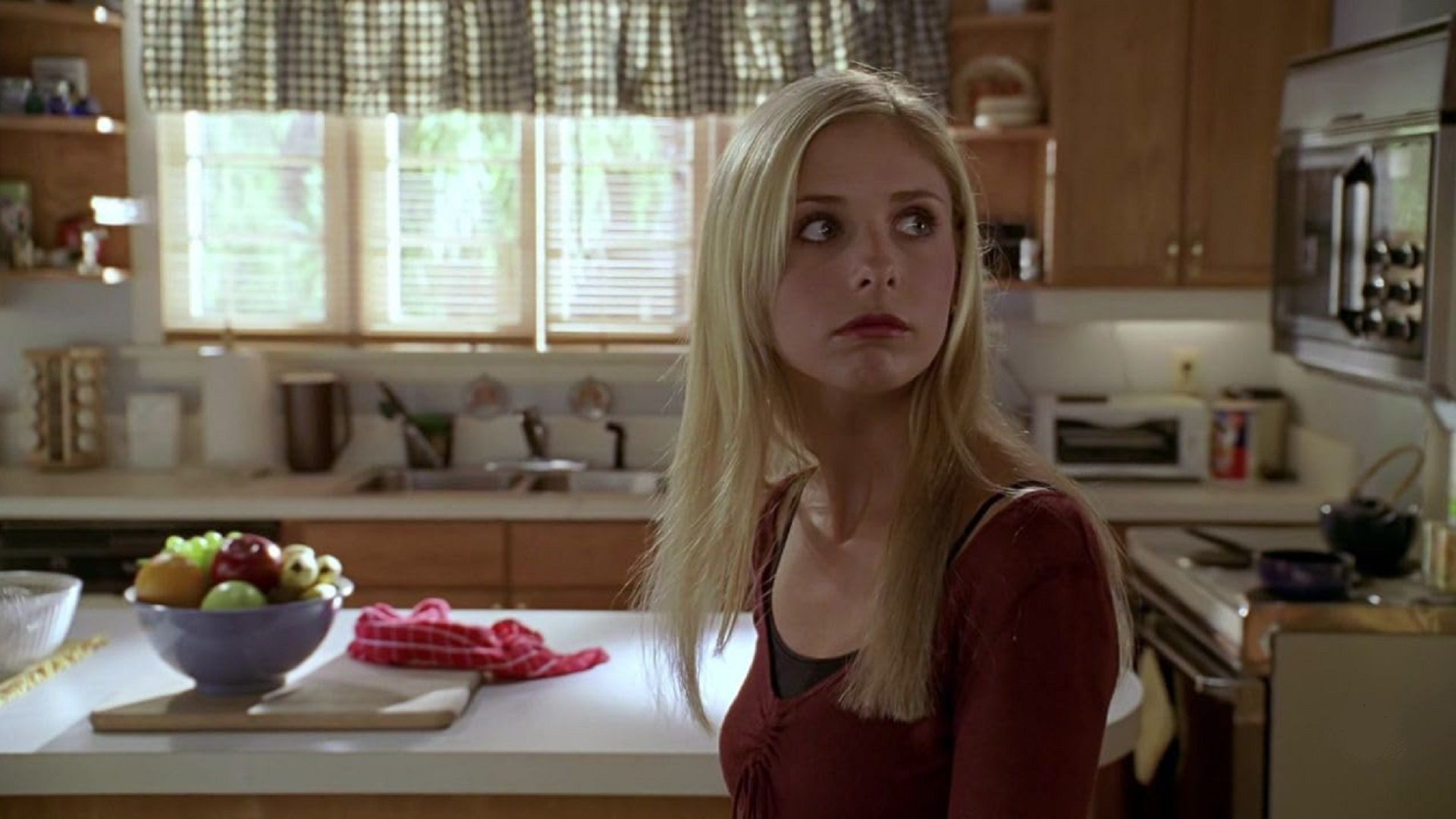 Sarah Michelle Gellar as Buffy looks to the side, judging in the kitchen