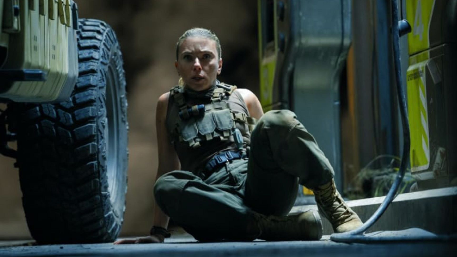 A frightened Scarlett Johansson sits on the floor in a battle suit