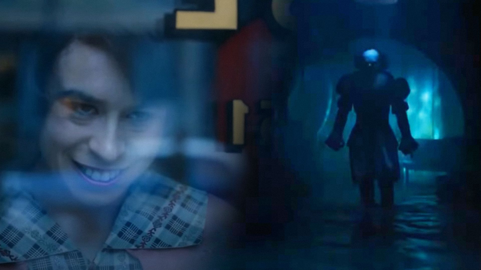 A girl with black hair smiles while leaning against a glass door, actor Bill Skarsgård in a clown suit stands in the darkness