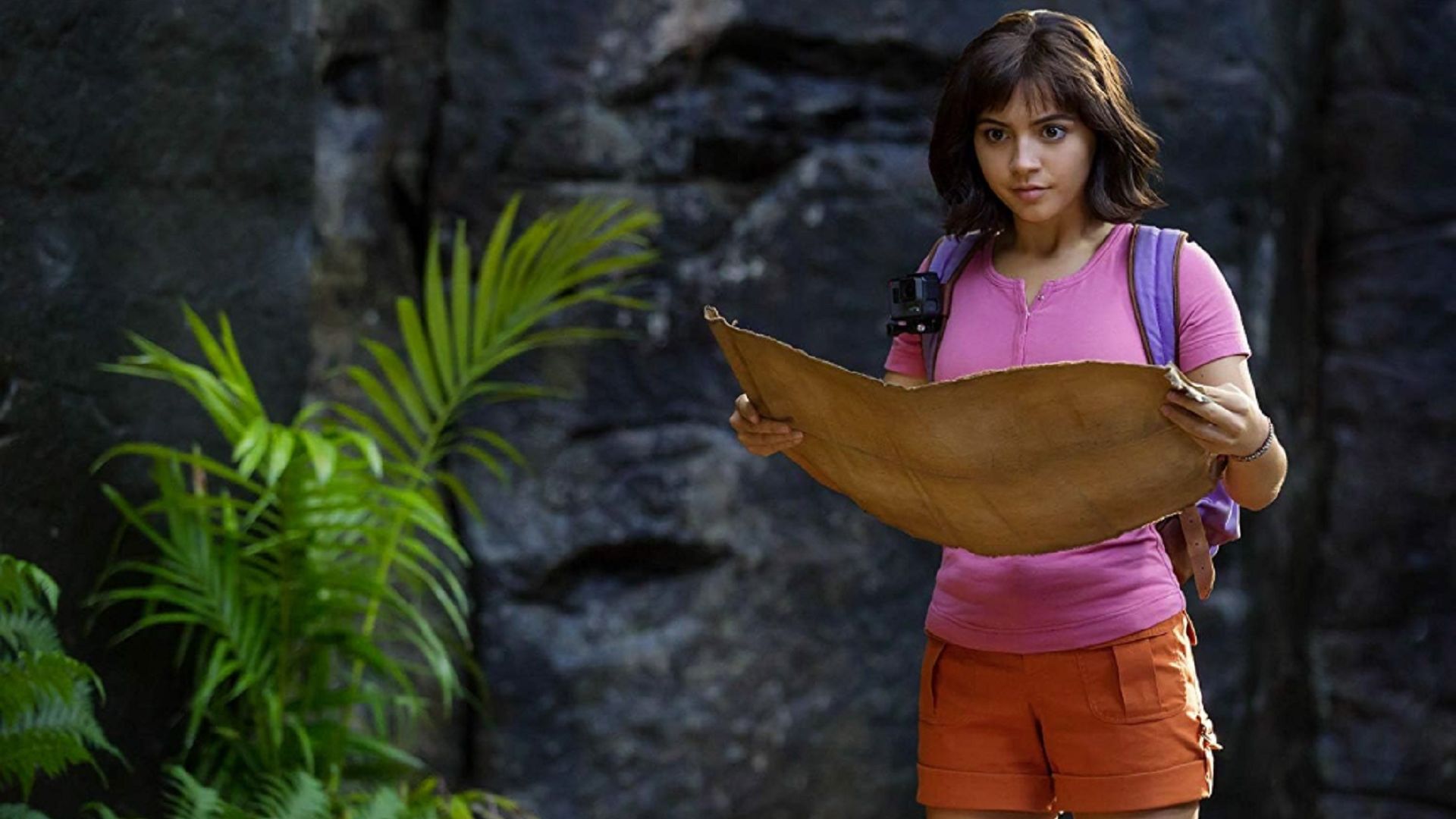 Dora the Explorer looks ahead, unfolding a map before her