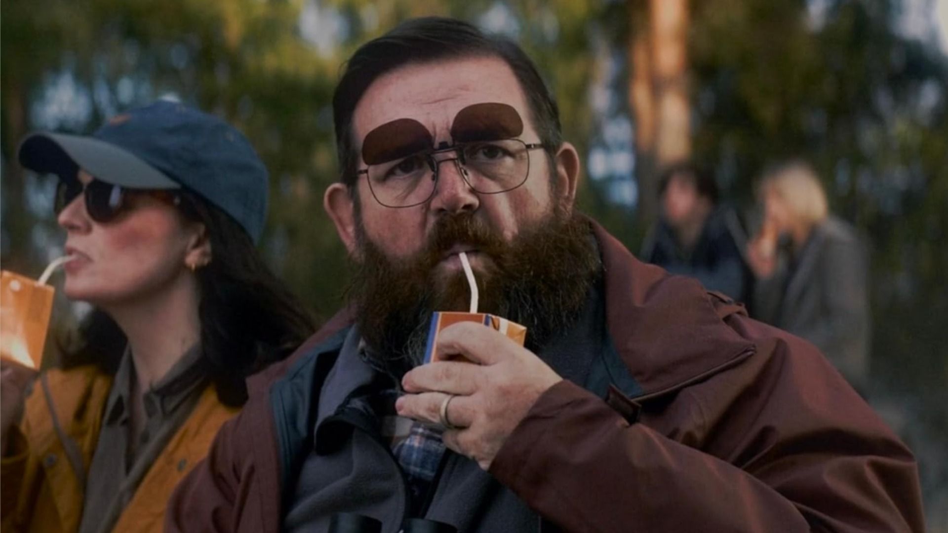 Actor Nick Frost in glasses drinks juice from a cardboard box through a straw and looks at the camera