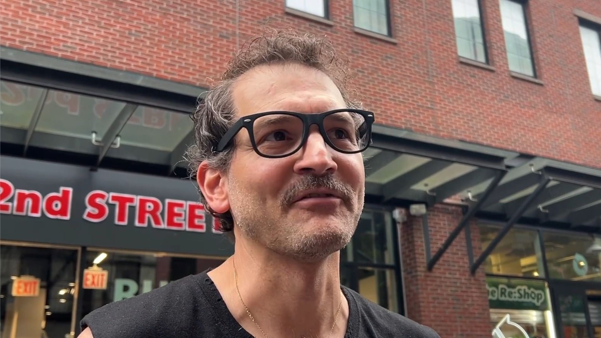 The Daily Show lighting technician George Guntas in a black tank top and glasses