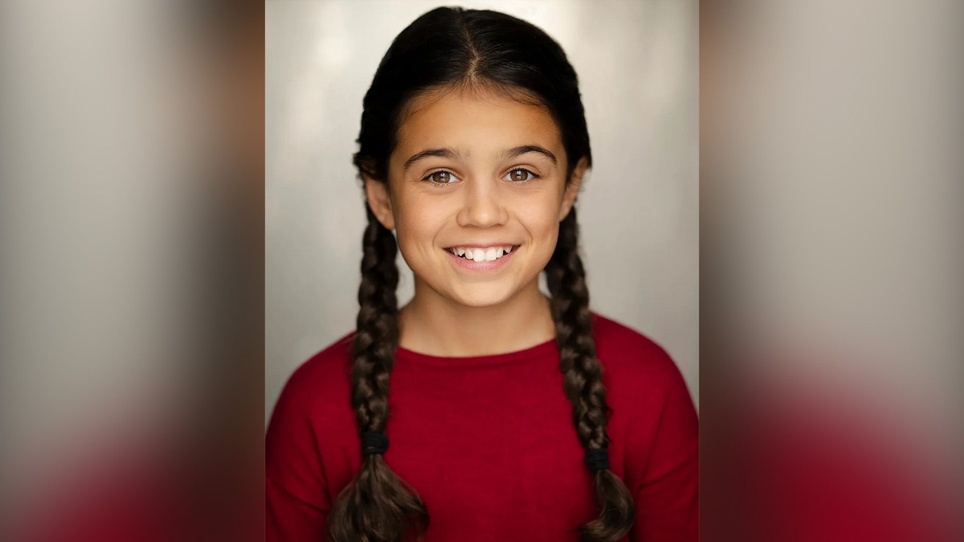 Actress Arabella Stanton with two braids wearing a red sweater