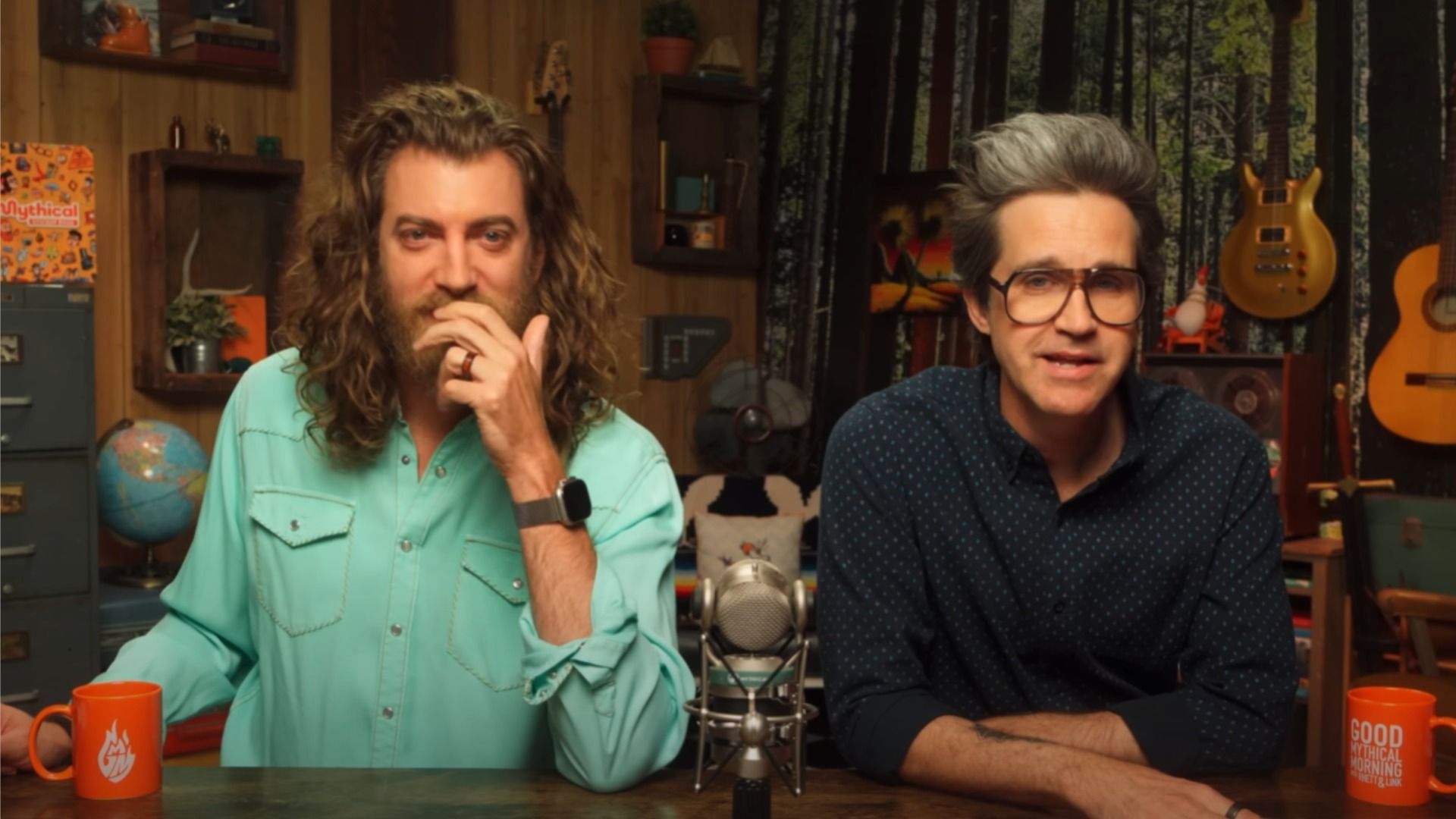 Bloggers Rhett and Link in shirts sitting at a table by the microphone