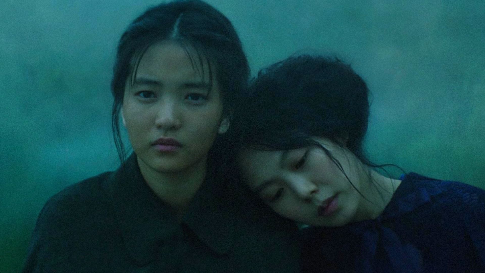 Two girls in black clothing, one of whom is resting her head on the other's shoulder
