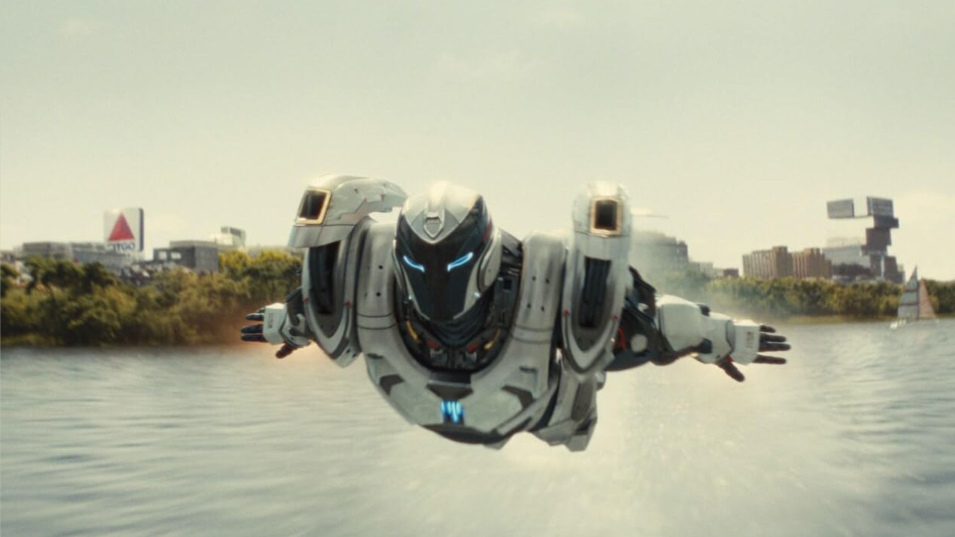 A person in a high-tech white iron suit flies over water