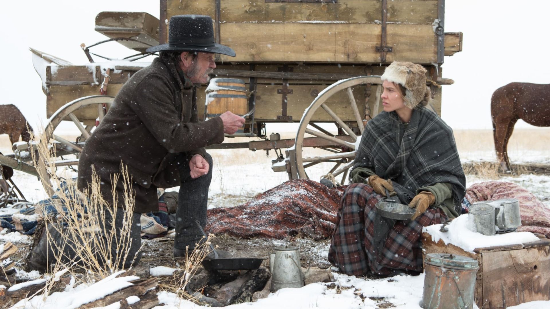 A man in a cowboy hat leaning over with a fork toward a girl in old-fashioned clothing