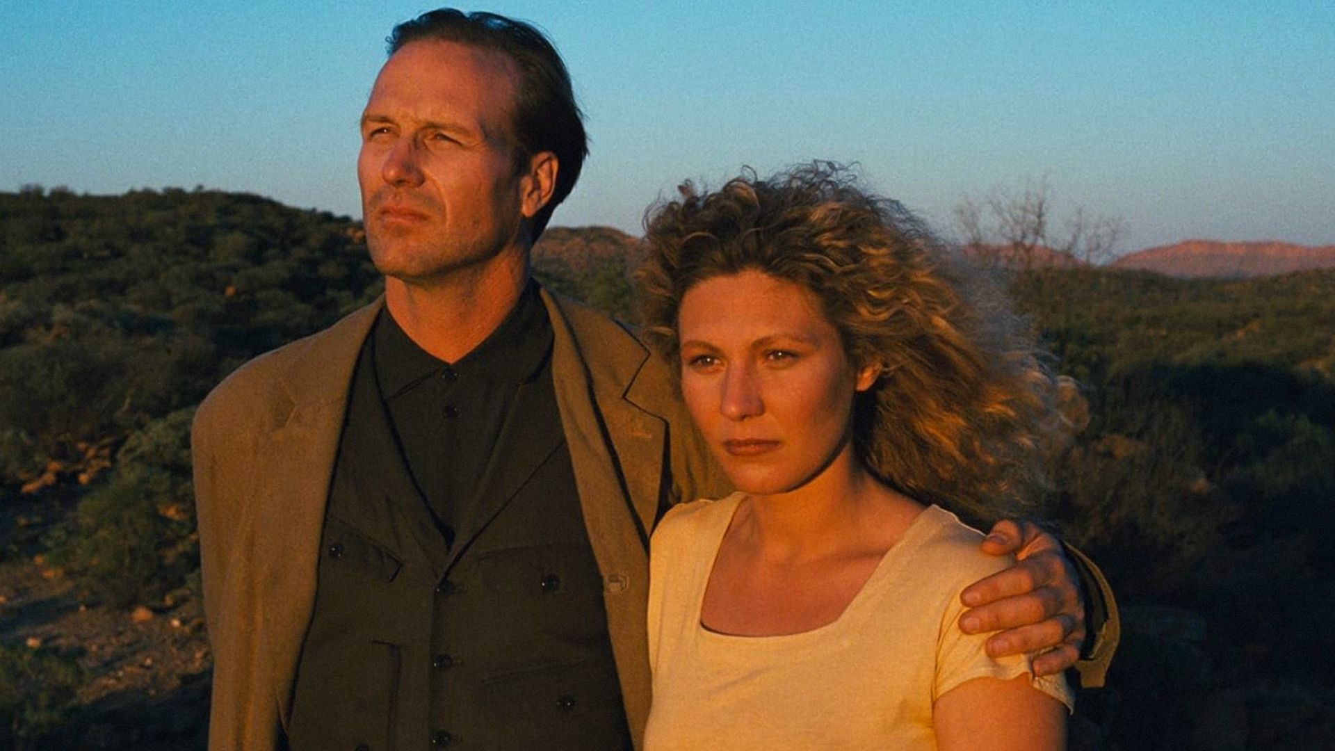 Actor William Hurt in a brown jacket embraces actress Solveig Dommartin in a white t-shirt