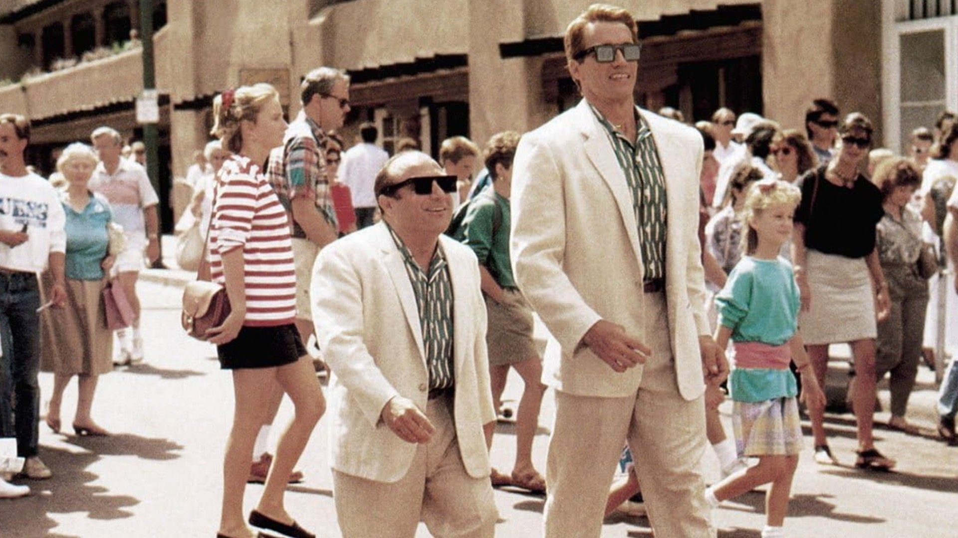 Danny DeVito and Arnold Schwarzenegger in white suits walking side by side