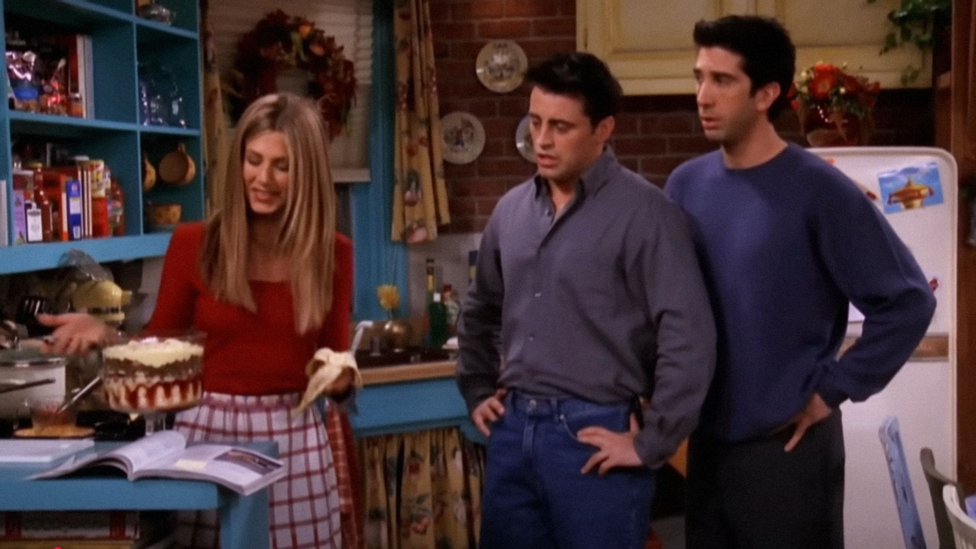 Actors Jennifer Aniston, David Schwimmer, and Matt LeBlanc looking at a clear baking dish with casserole