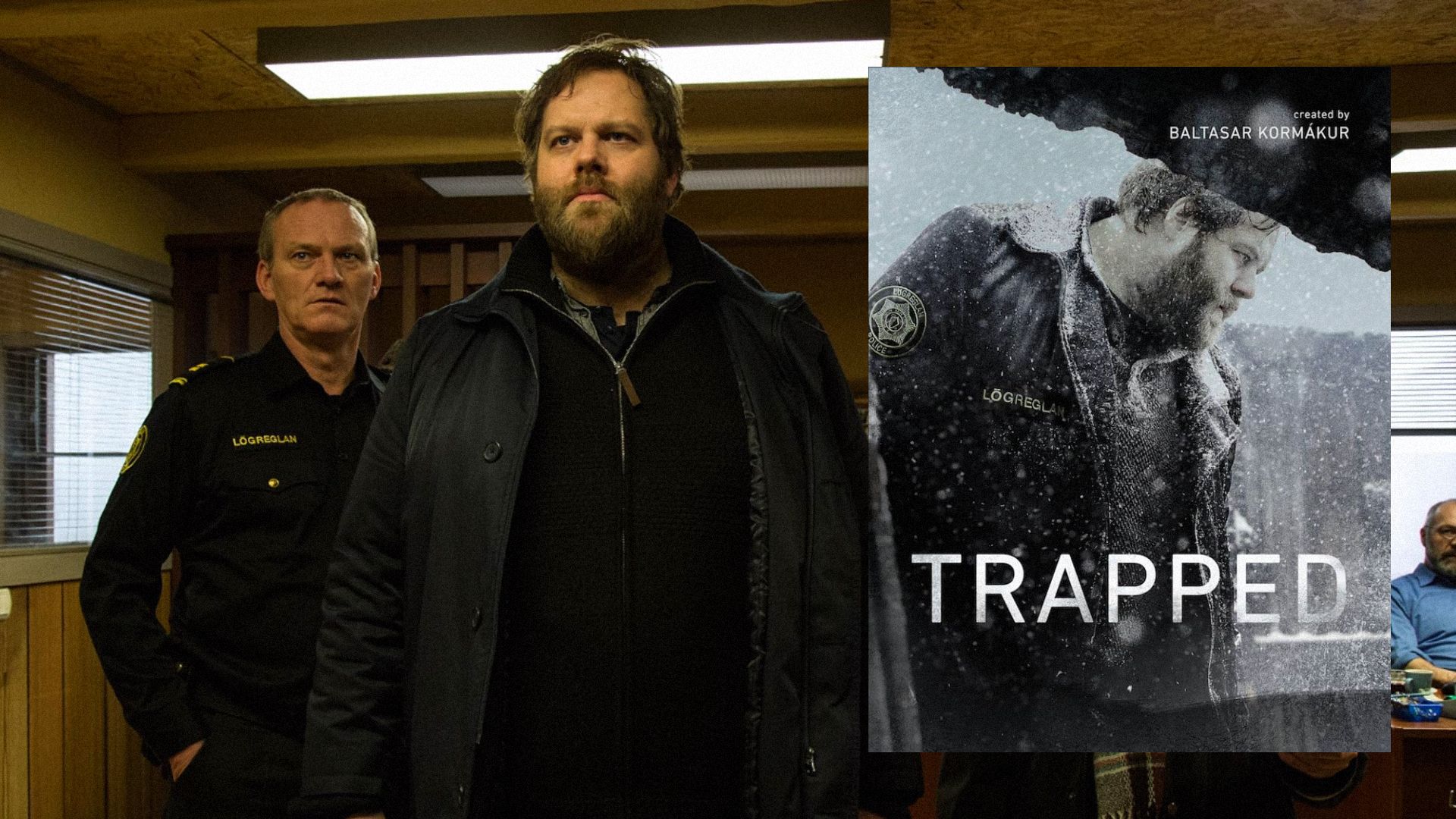 Two men standing in a room wearing black clothing, next to a poster depicting a man standing in the snow