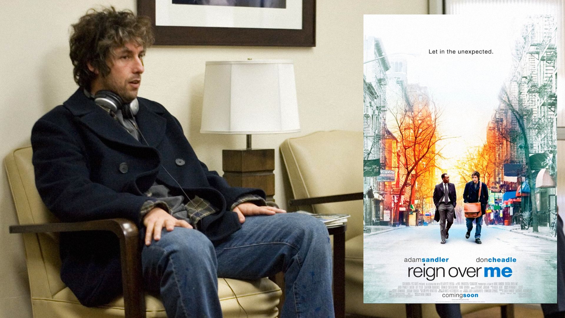 Actor Adam Sandler in a black coat sits in a chair next to a movie poster featuring him walking down the street