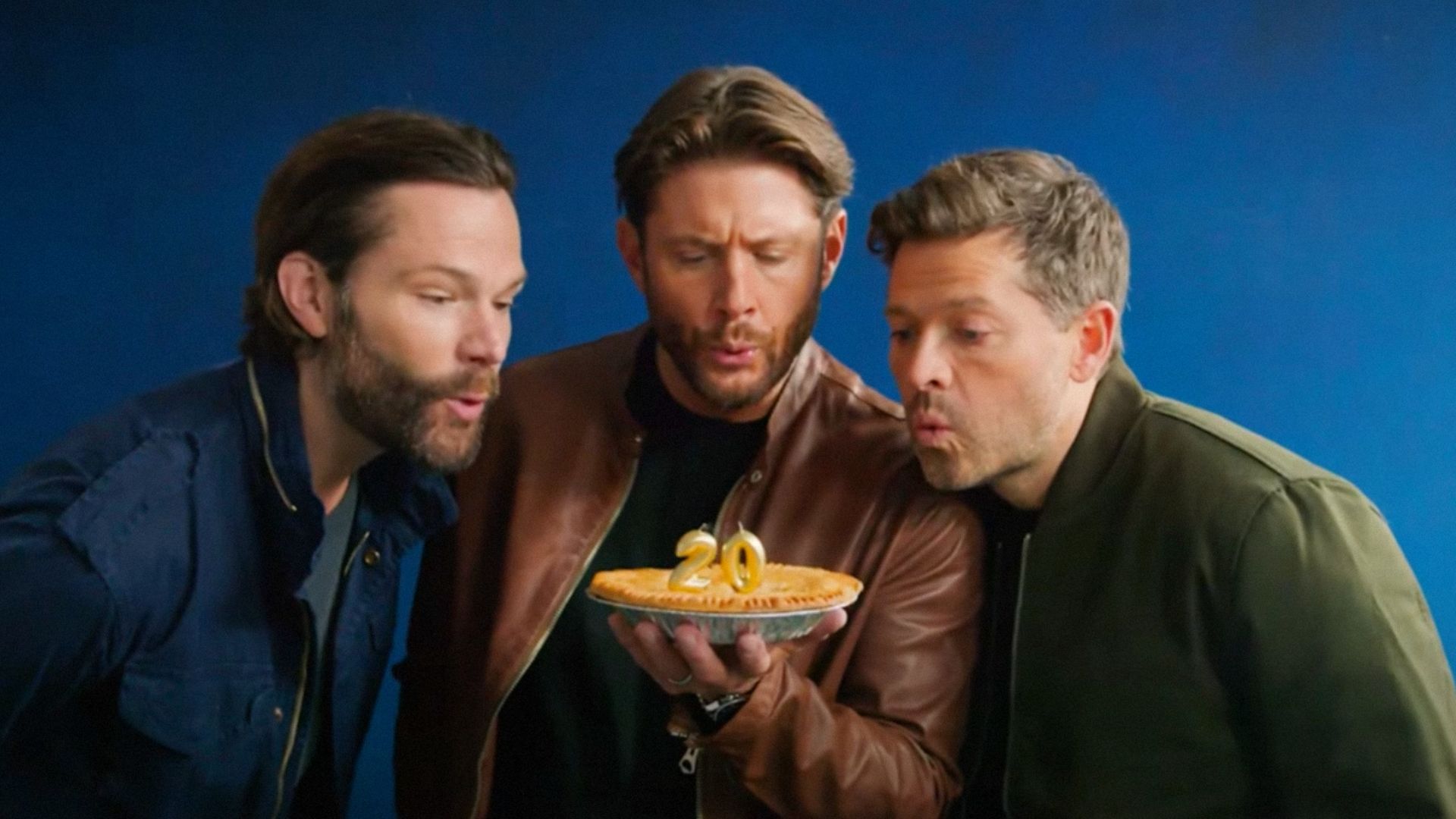 Actors Jared Padalecki, Jensen Ackles and Misha Collins blow out candles on a cake