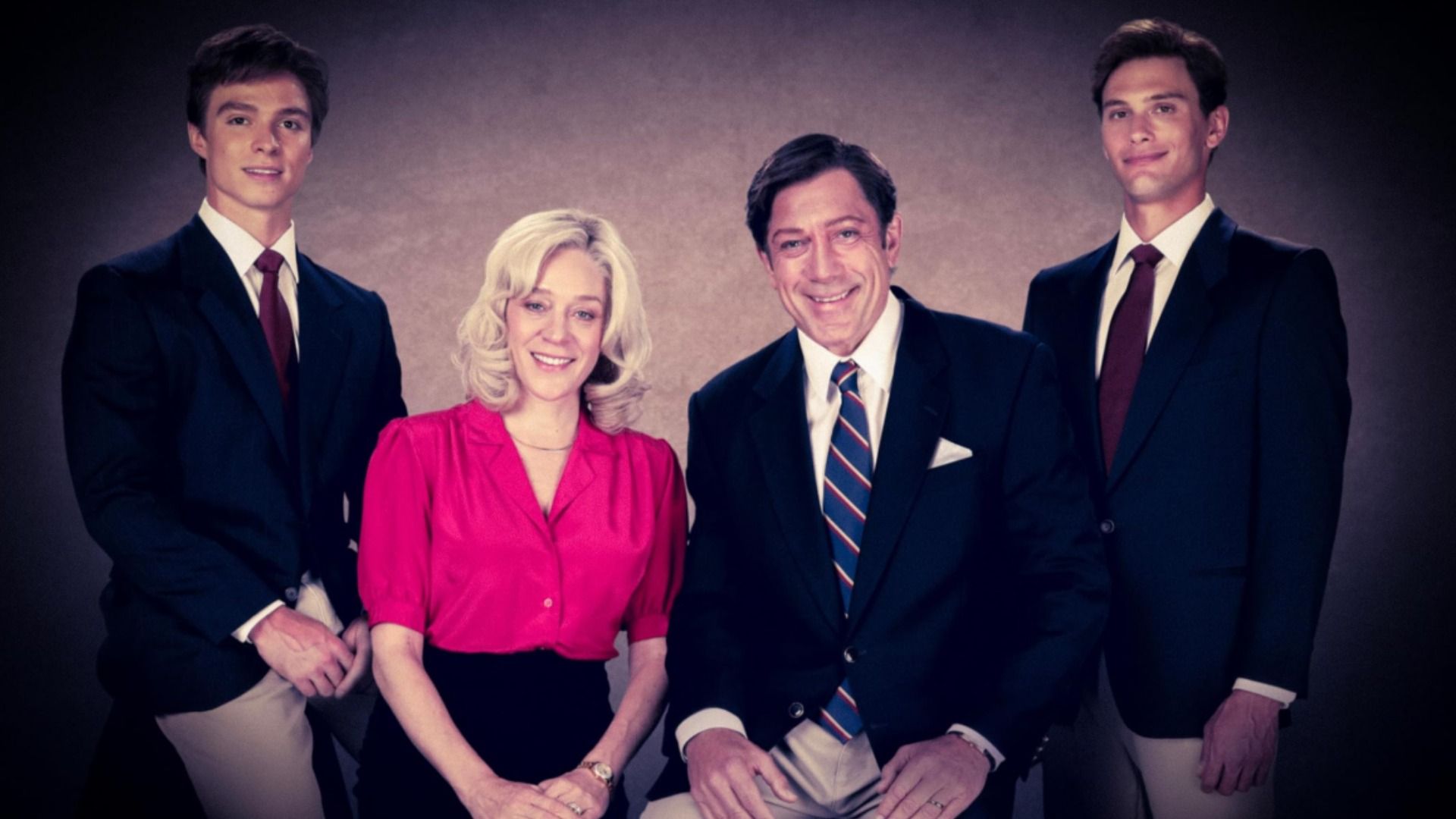 A man, woman and two young men in suits in a family photograph, smiling