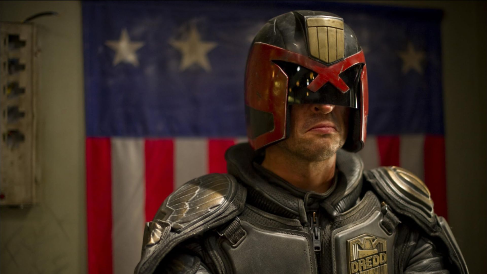 Actor Karl Urban in a gray futuristic suit and black-red helmet