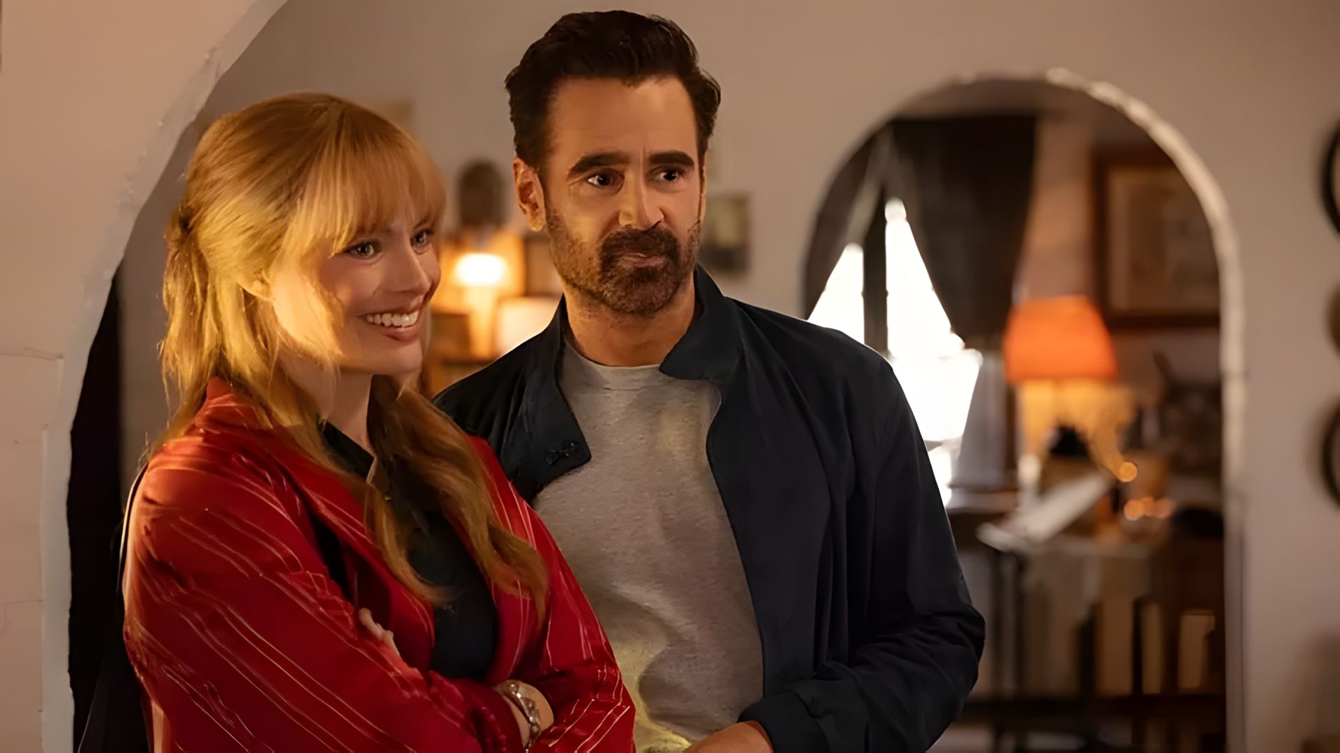 Margot Robbie and Colin Farrell standing next to each other in a cozy room with soft warm lighting