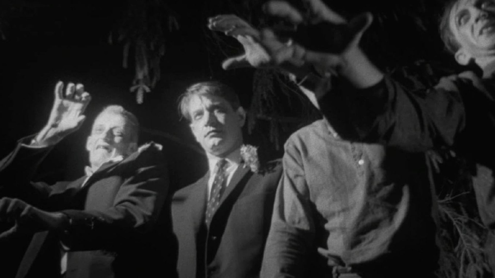 Men in suits and zombie costumes stretching their arms forward