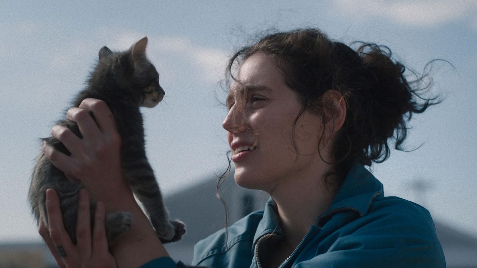 Girl in blue jacket holding a gray kitten