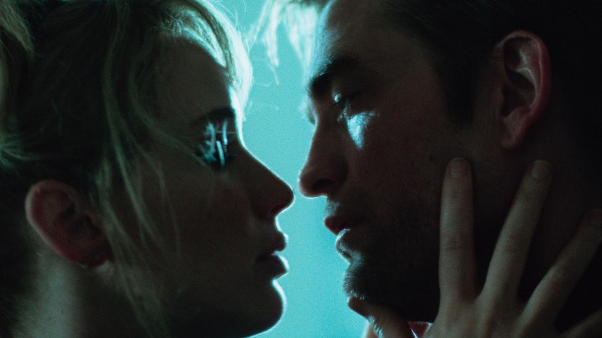 Actors Jennifer Lawrence and Robert Pattinson look into each other's eyes against a blue background