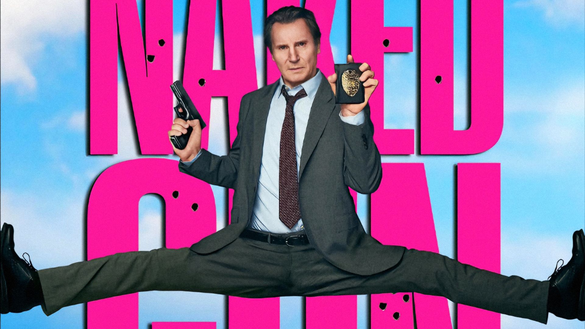 Actor Liam Neeson sits in a split holding a gun and police badge