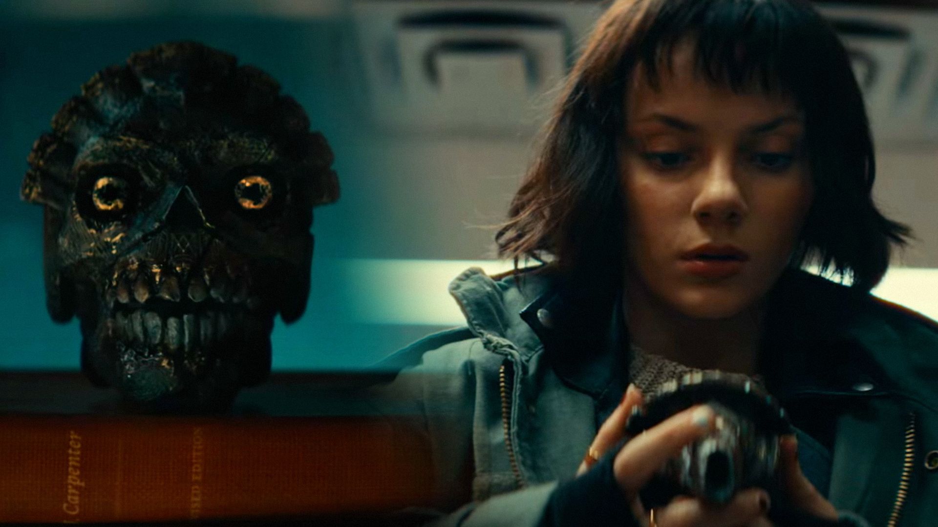 Metal skull, on the right actress Dafne Keen in a green jacket holds this skull in her hands