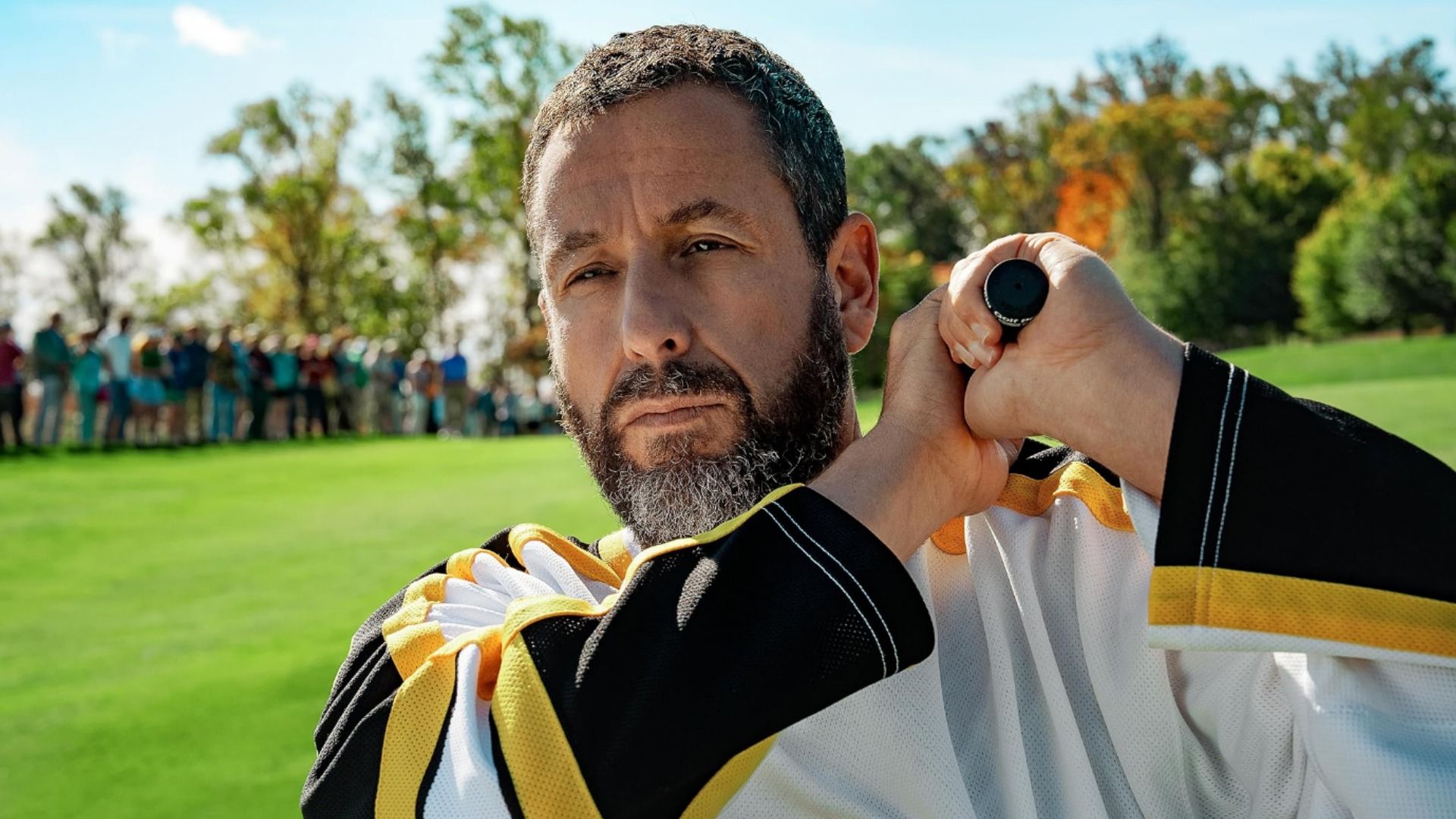 Actor Adam Sandler holding a golf club standing on a golf course