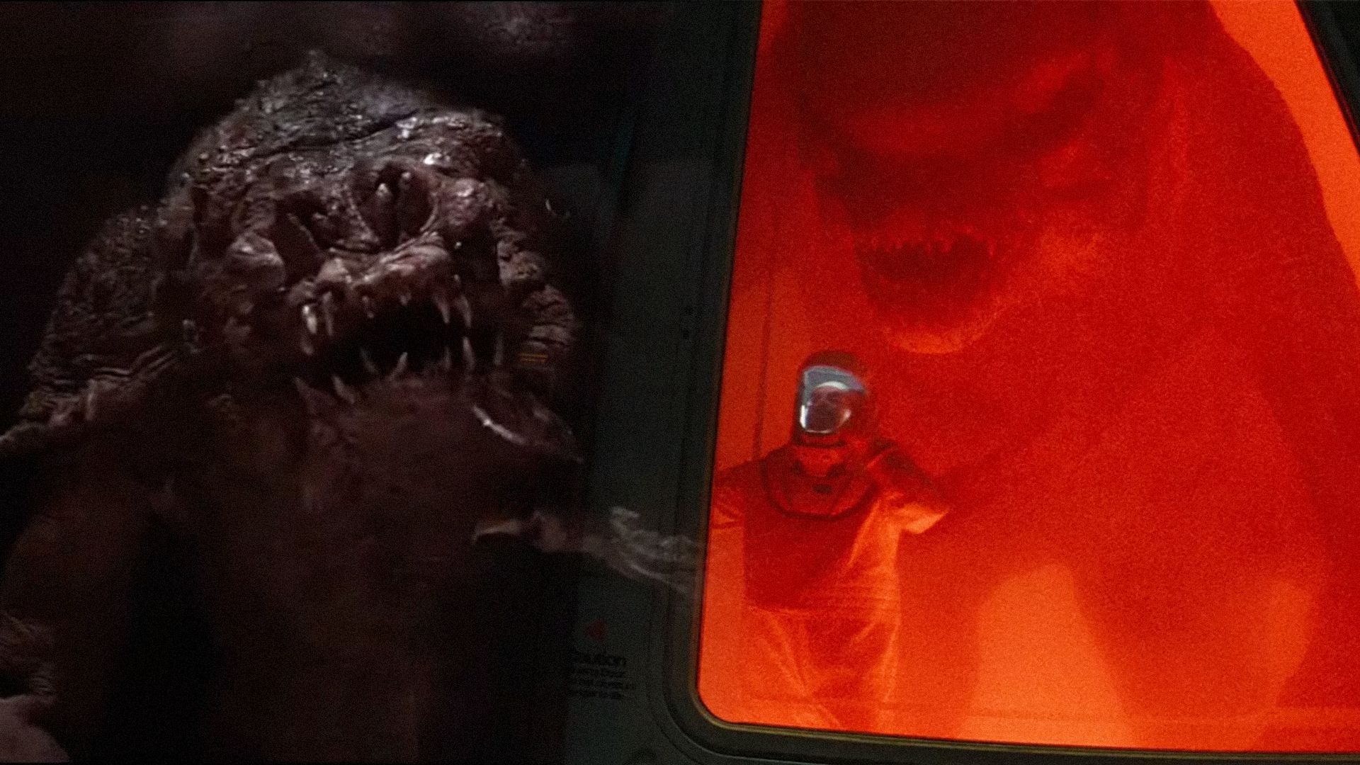 Monster with a huge head, with a similar monster sitting behind glass in a laboratory nearby