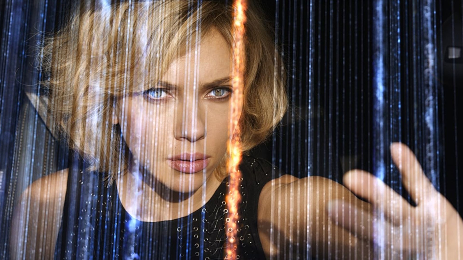 Actress Scarlett Johansson in a black dress with her hand raised among shimmering lines
