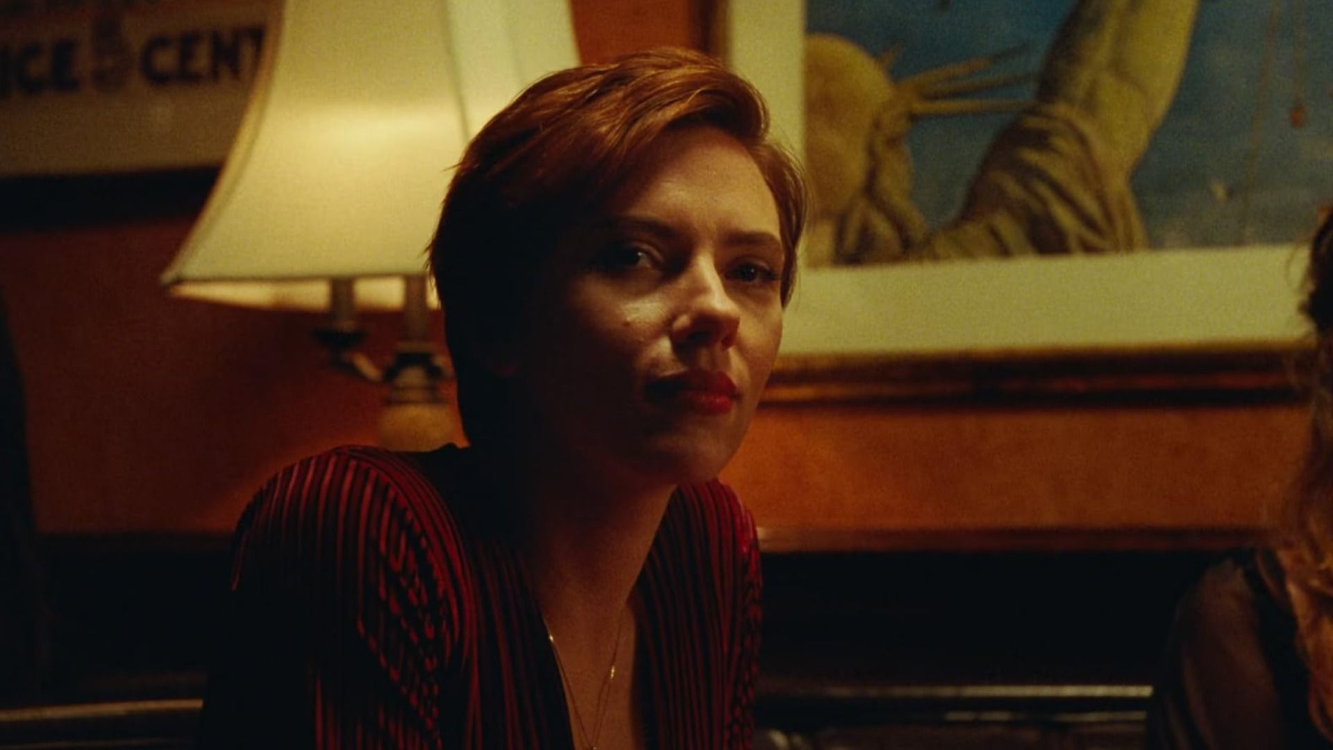 Actress Scarlett Johansson in a red blouse sits next to a lamp