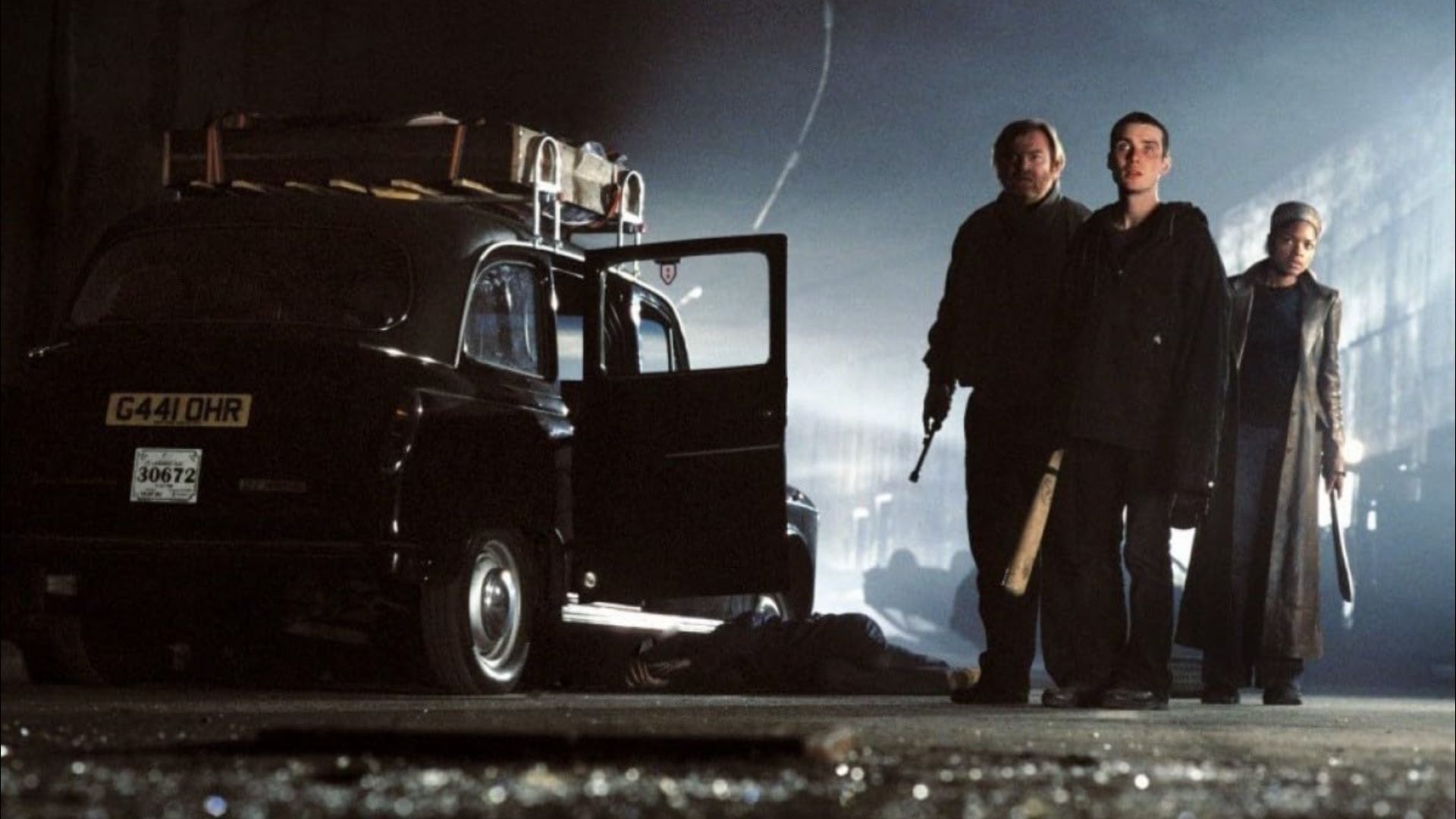 Two men and a girl in dirty clothes standing next to a black car