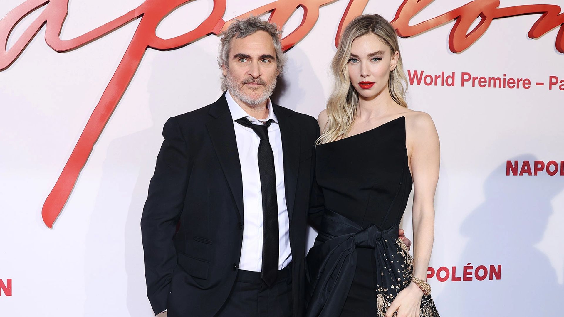 Joaquin Phoenix and Vanessa Kirby pose on the red carpet at the "Napoleon" film premiere, both wearing elegant black outfits