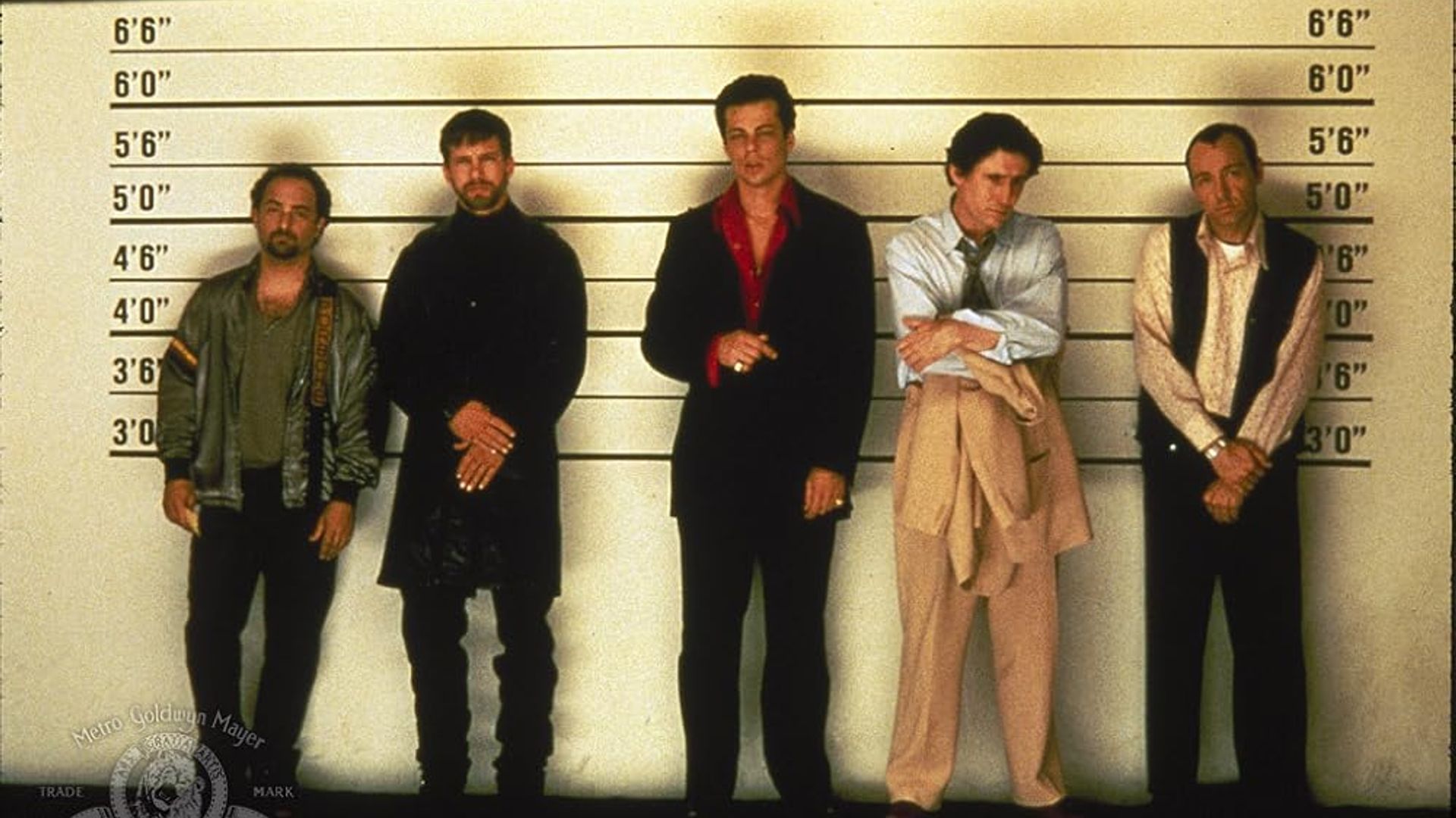 Five men standing against a height measurement wall like in a police lineup