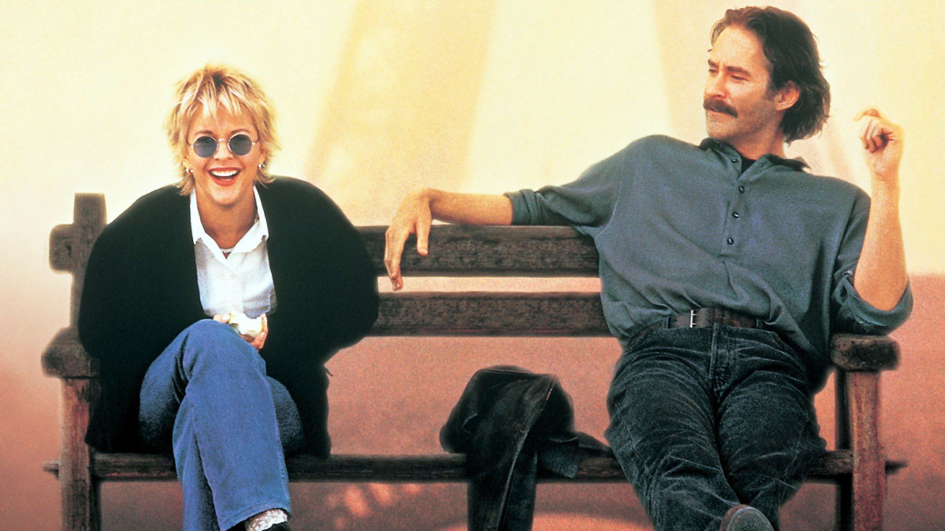 Meg Ryan and Kevin Kline sitting on a bench, talking and laughing