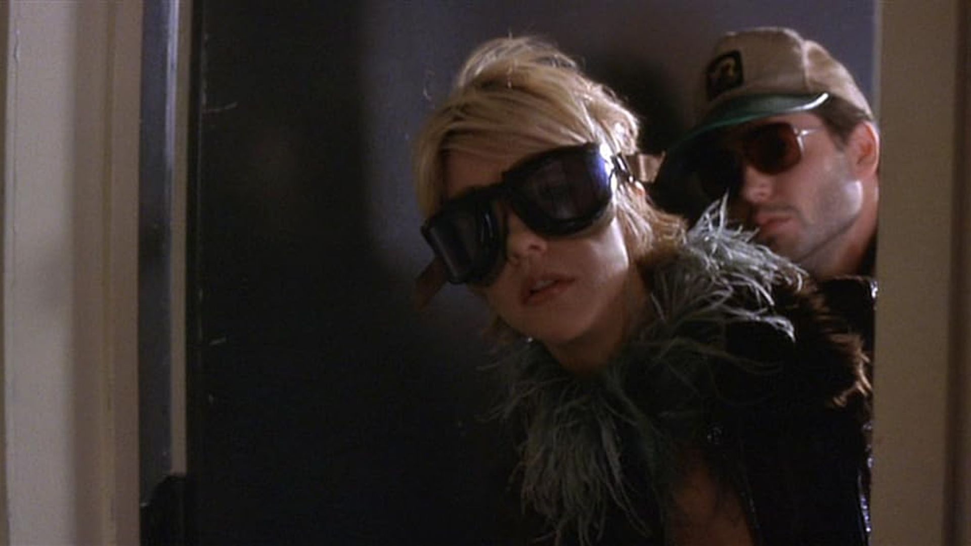 Meg Ryan and Matthew Broderick in dark sunglasses peeking out from behind a door