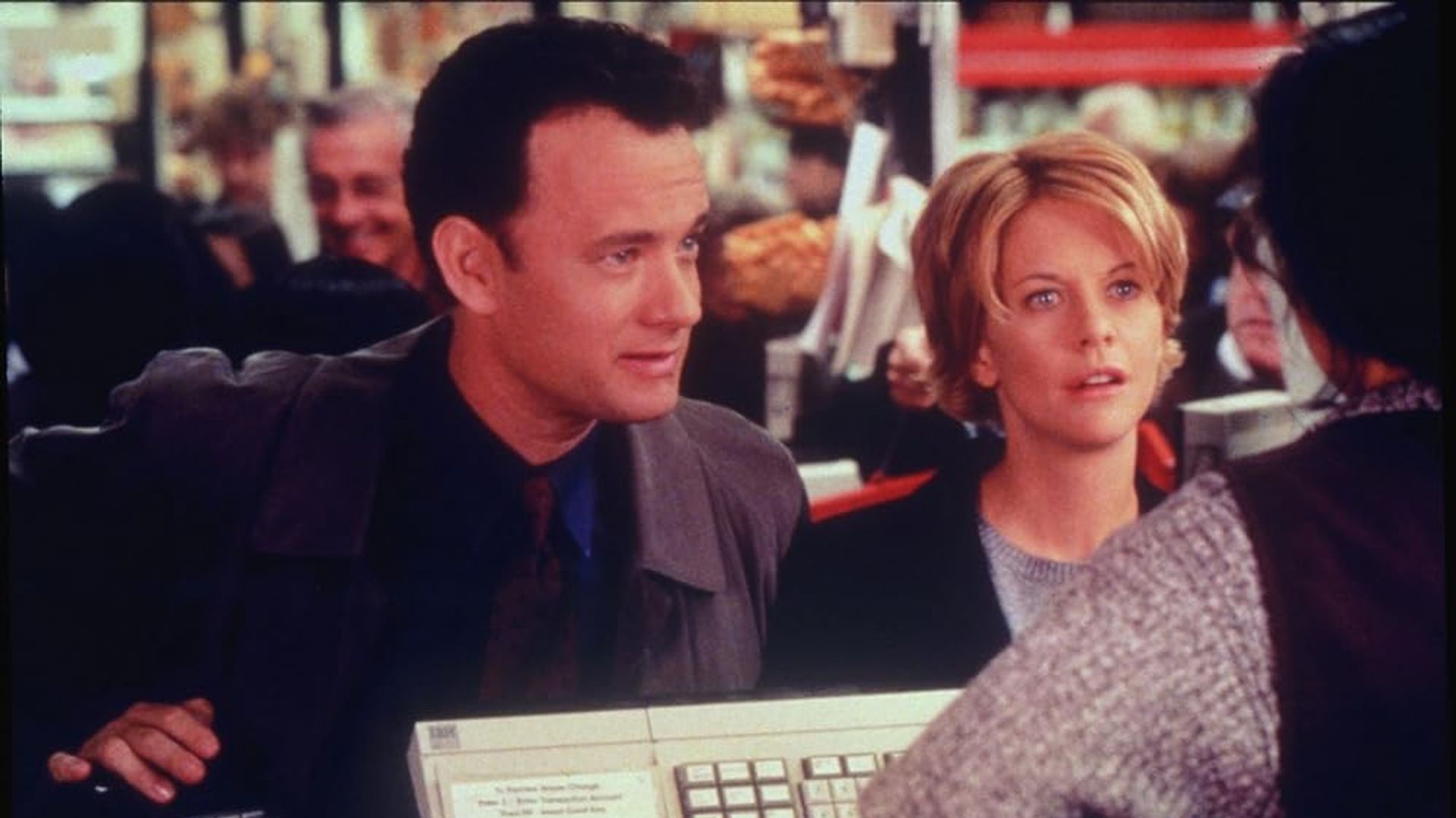 Tom Hanks and Meg Ryan standing at the checkout counter in a store, talking to the cashier