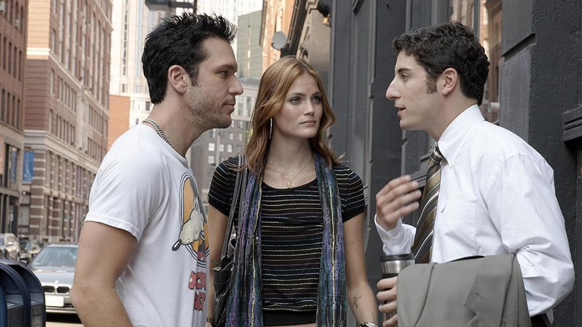 Two men and a woman talking on the street between buildings in the city