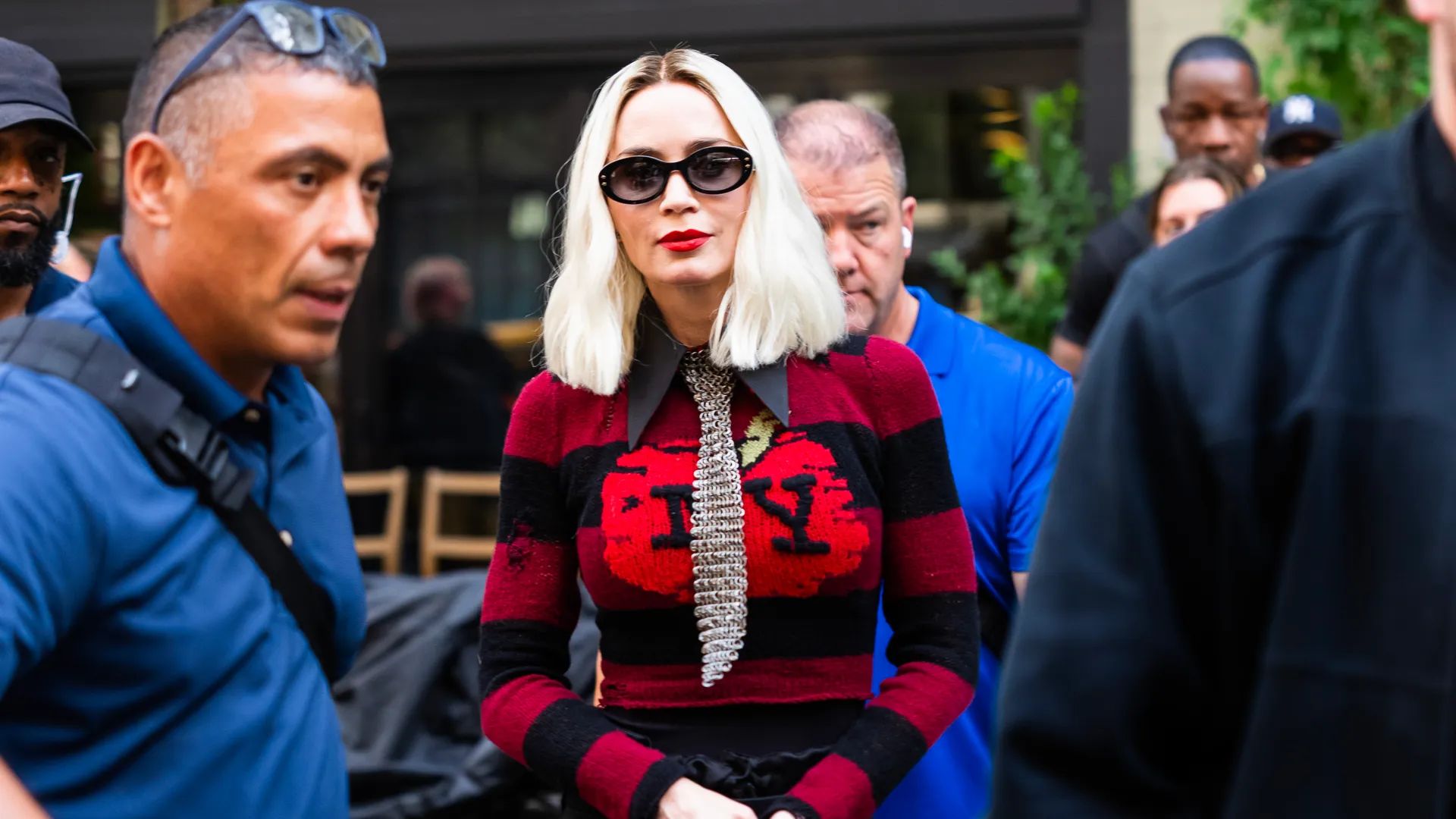 Emily Blunt with platinum bob in red sweater with NY lettering