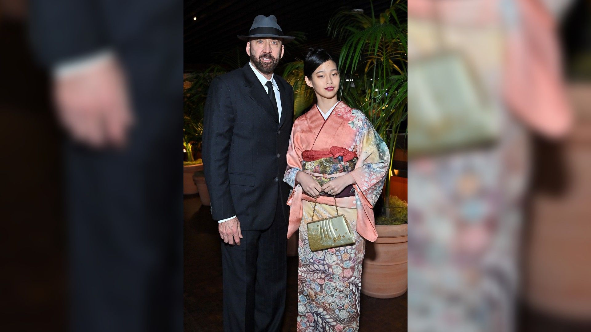 Nicolas Cage in a black suit and hat and Riko Shibata in a pink patterned kimono
