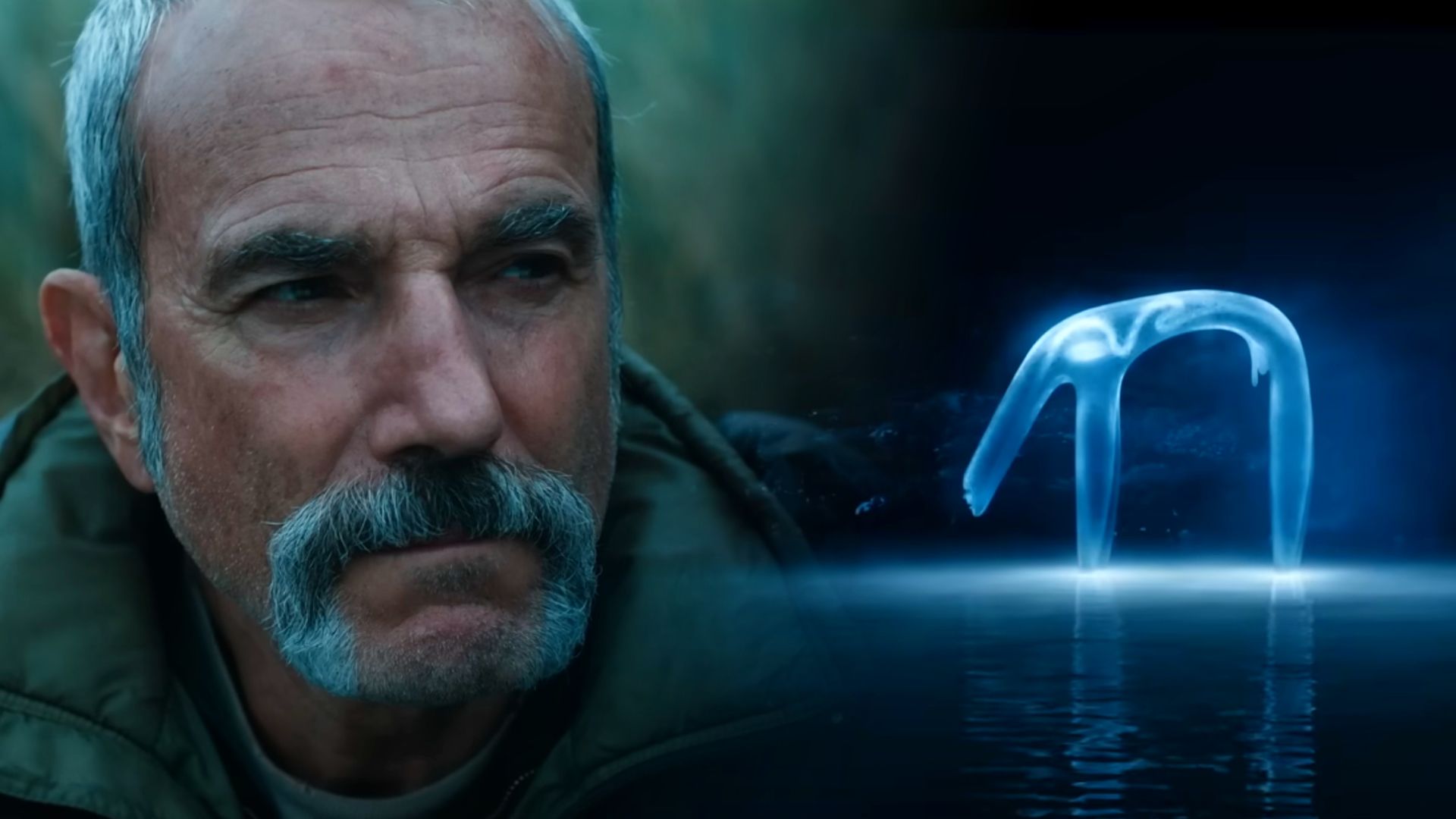 Actor Daniel Day-Lewis in a green jacket and a translucent bluish creature standing on water