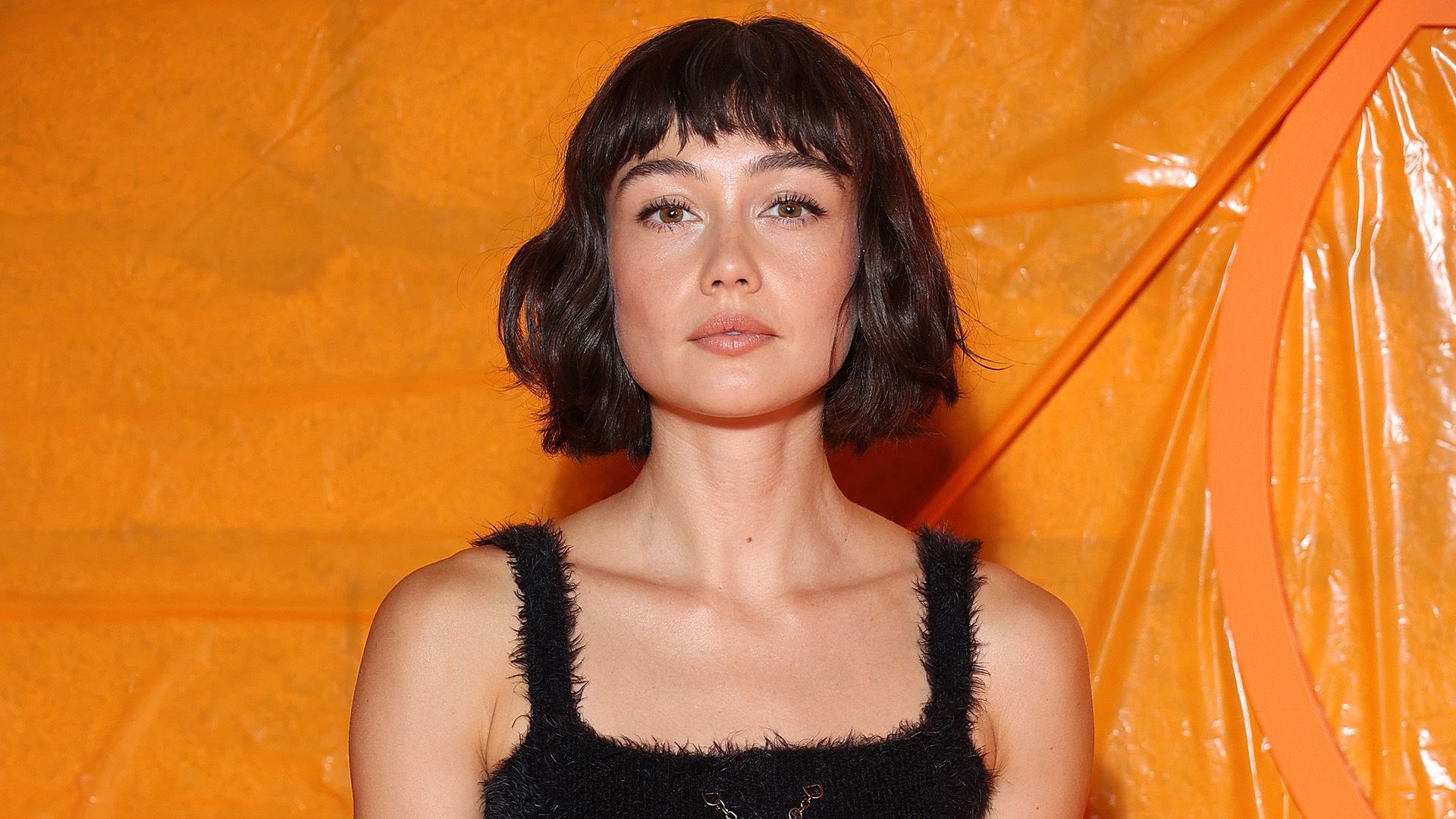 Actress Sydney Chandler against an orange background