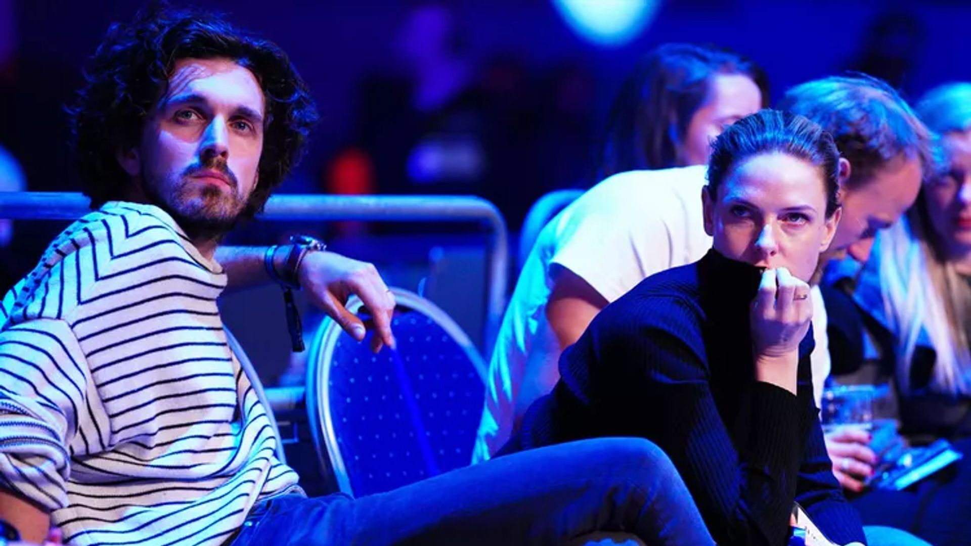 Rebecca Ferguson and Rory St. Clair Gainer sitting in a hall with neon lighting
