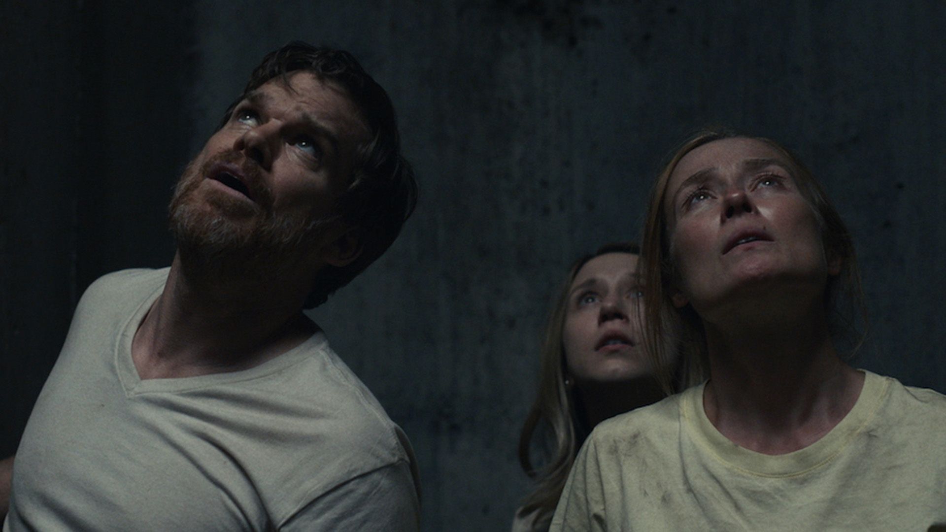 Michael C. Hall and two women in darkness looking upward