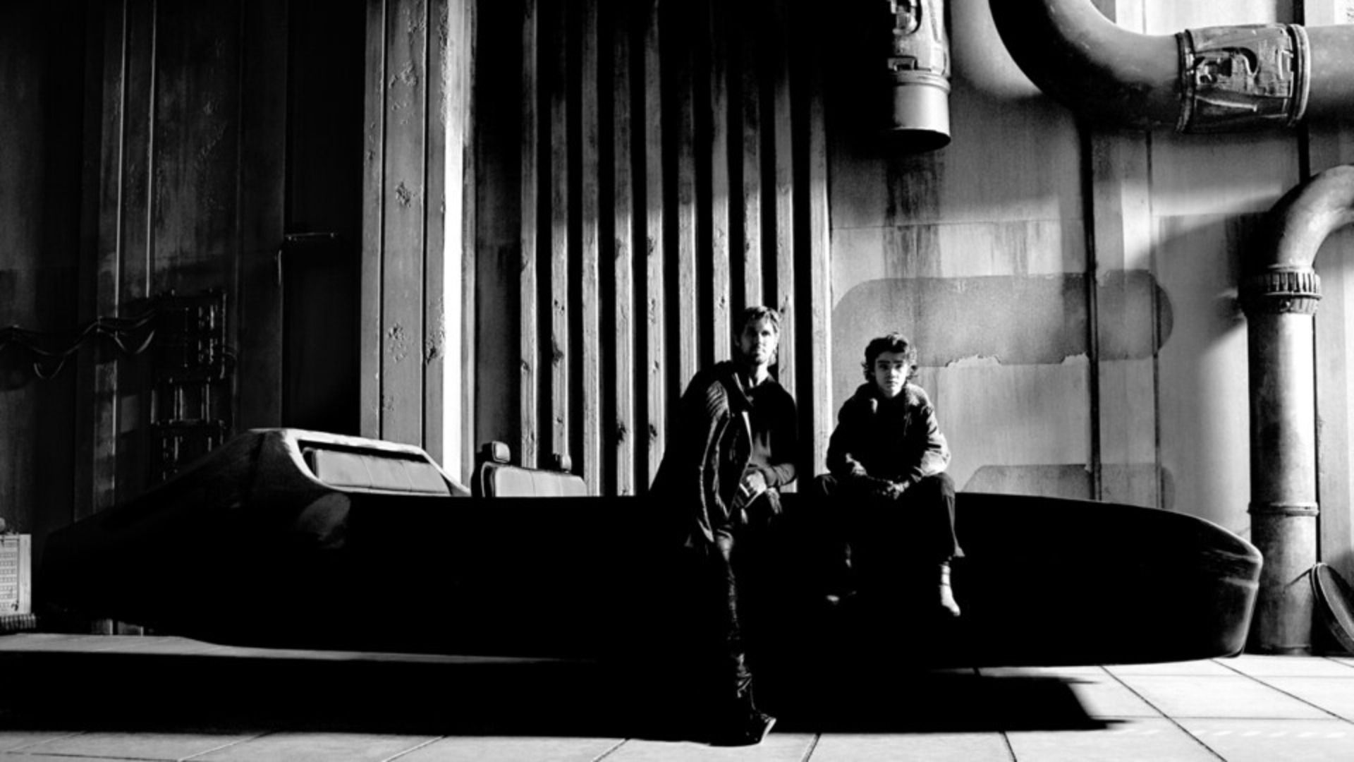 Actor Ryan Gosling sits with a child on the hood of a futuristic car without wheels