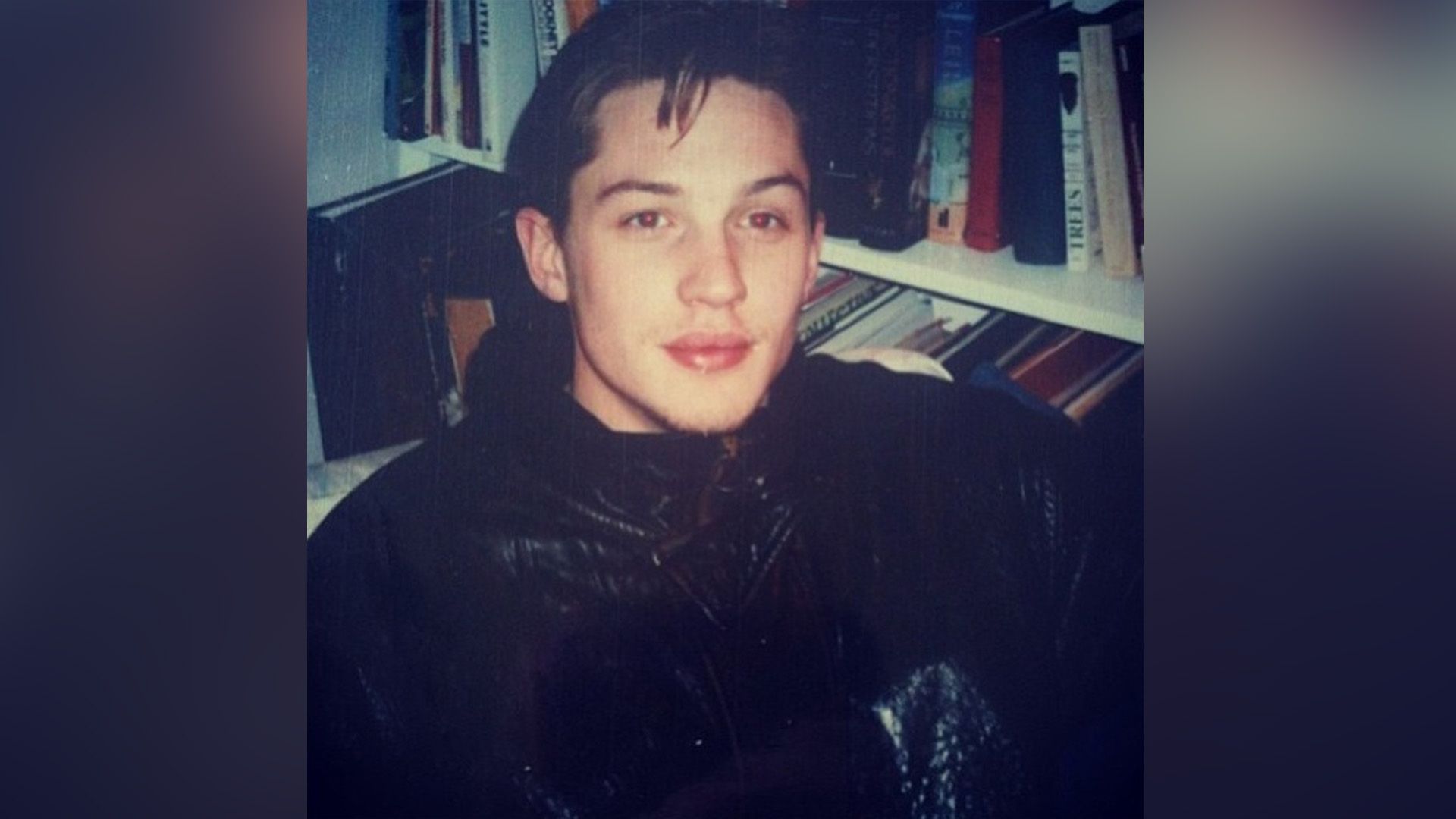 Young Tom Hardy next to a bookshelf