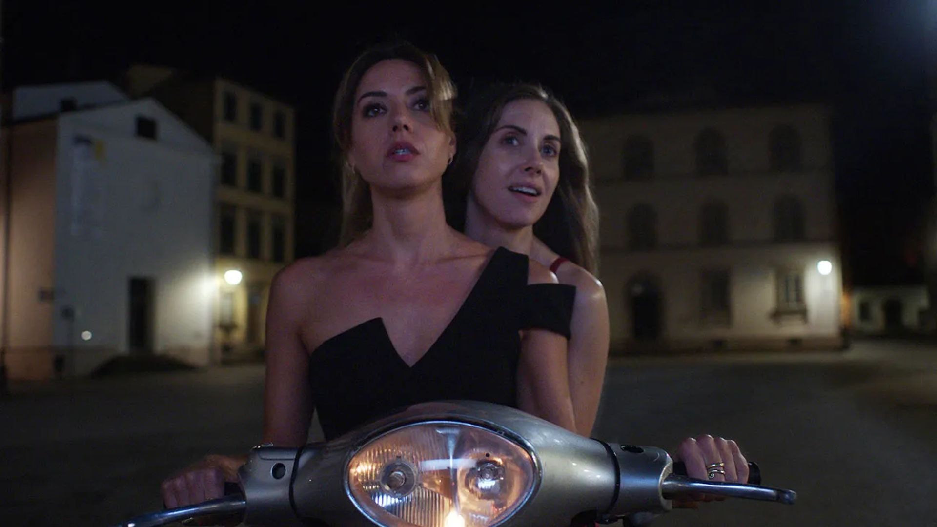 Alison Brie and Aubrey Plaza ride a motorcycle in the dark, a scene from "Spin Me Round"