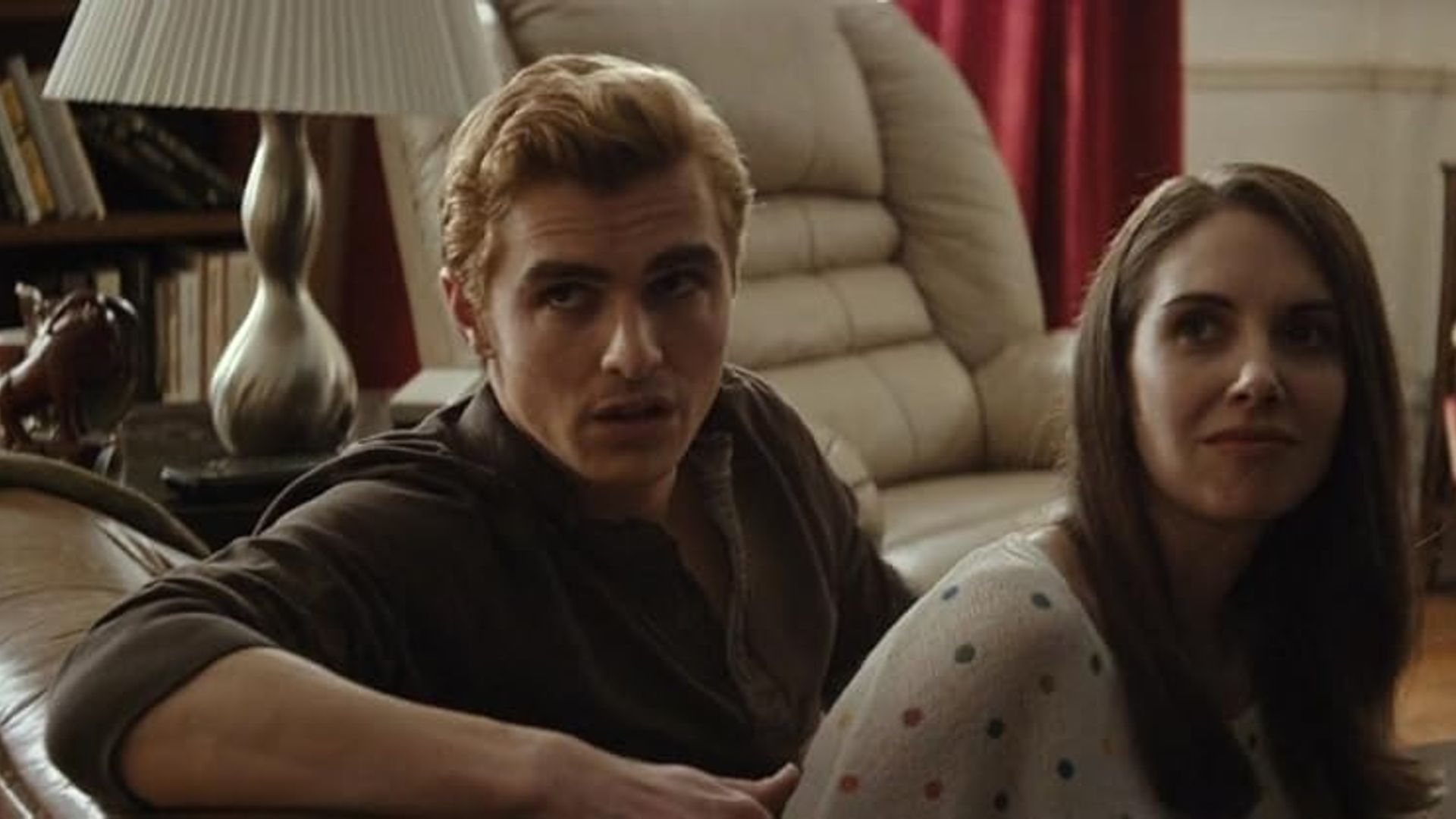 Alison Brie and Dave Franco sitting on a couch, turned halfway toward the camera
