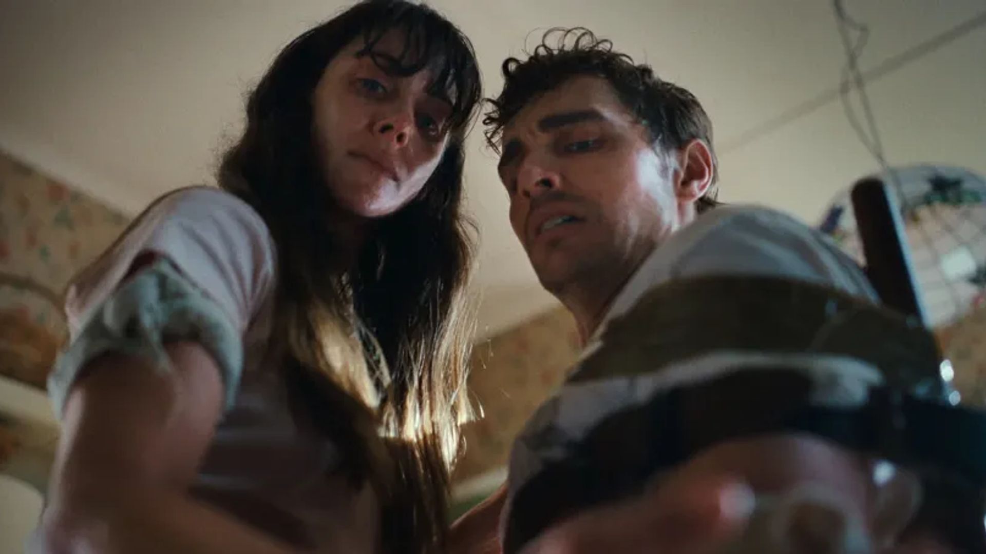 Alison Brie and Dave Franco look into the camera with worried expressions, shot from a low angle