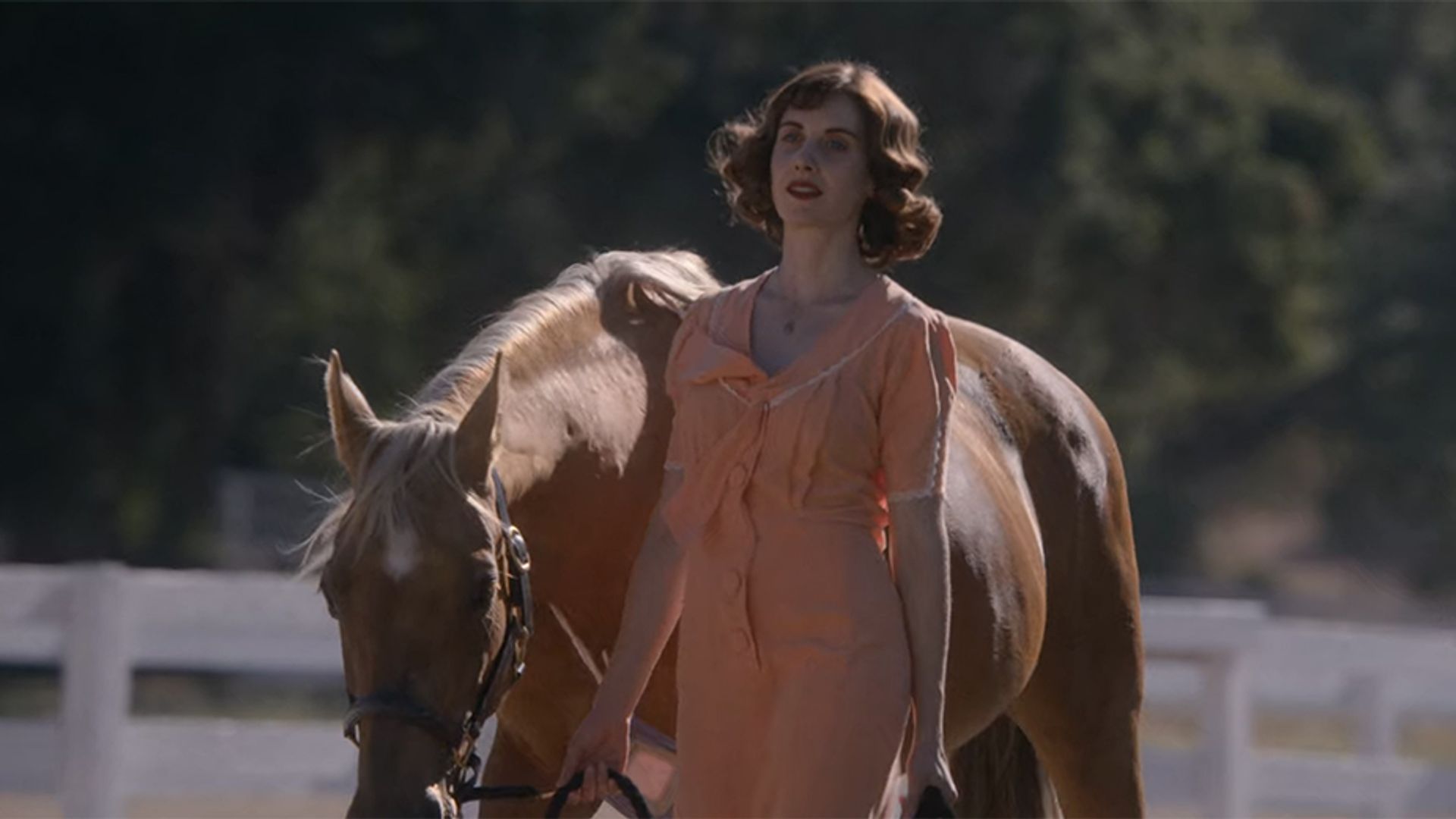 Alison Brie leading a horse by the reins, still from the film "Horse Girl"